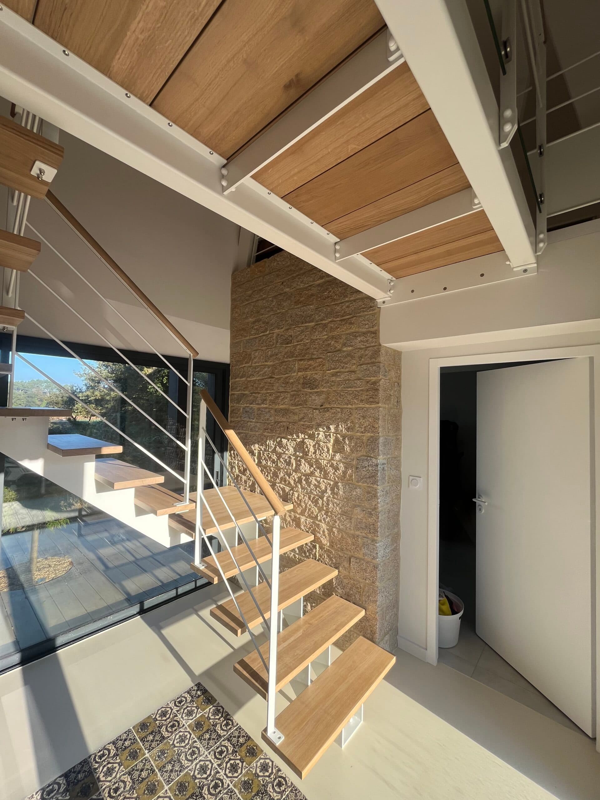 Maison contemporaine rénovée par AJY Maçonnerie avec extension bois, mur de clôture en pierre et cour en gravier en campagne bretonne.