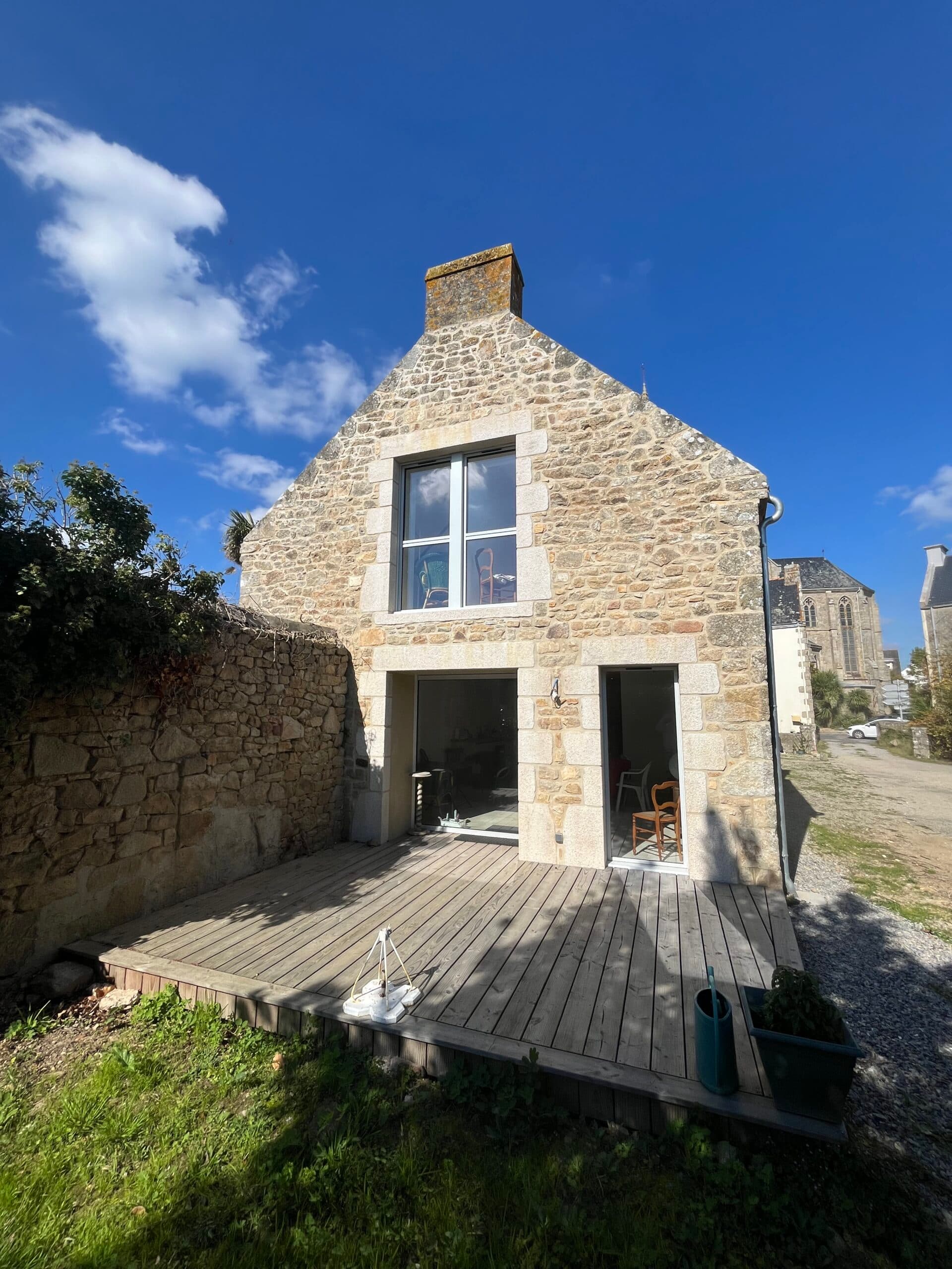 Longère traditionnelle en pierre proche d’une église, mise en valeur par les travaux de maçonnerie d’AJY Maçonnerie sur les façades et ouvertures.