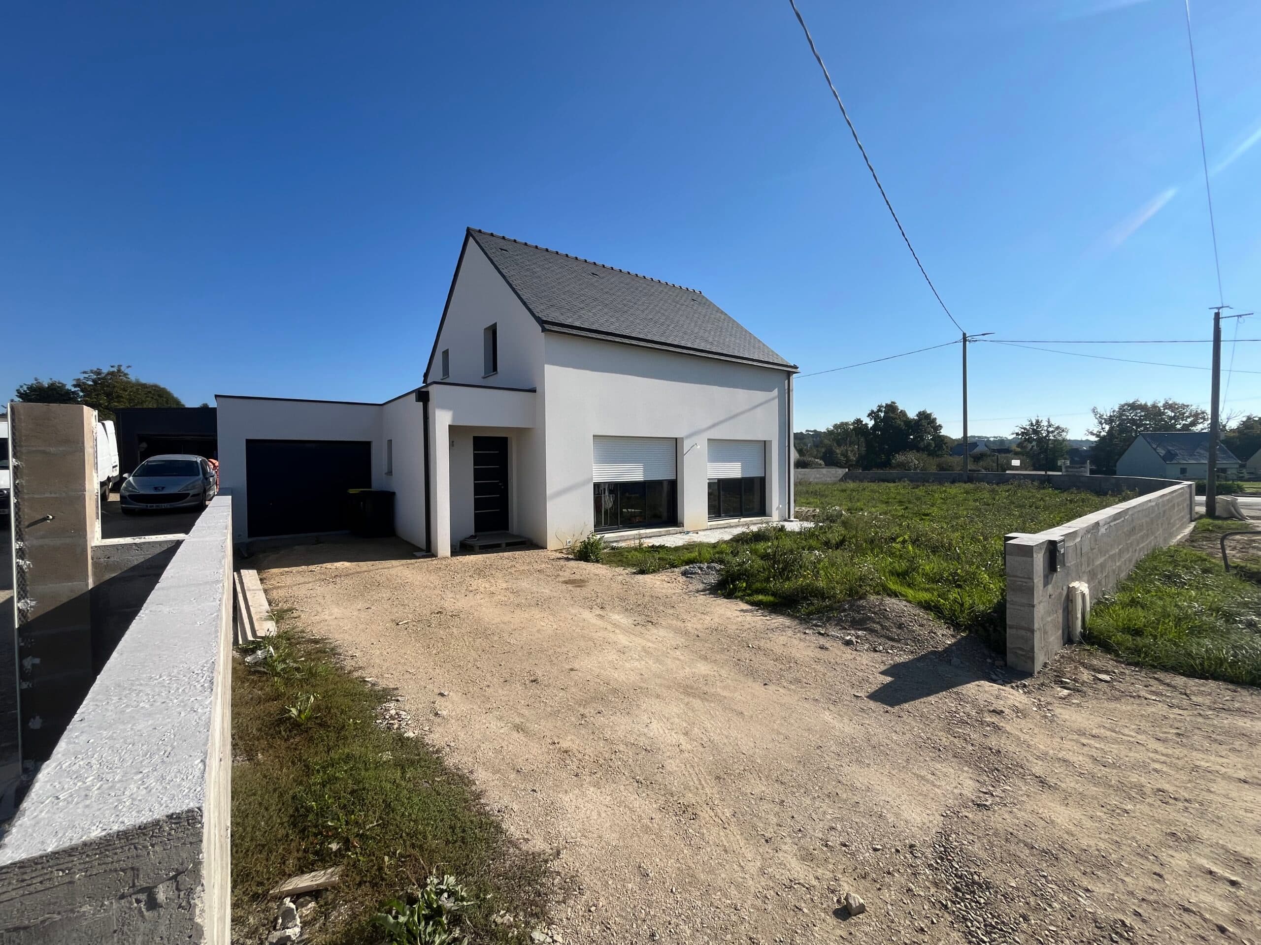 Maison neuve moderne avec garage accolé, enduit blanc et terrain en cours d’aménagement réalisée par AJY Maçonnerie dans le Morbihan.